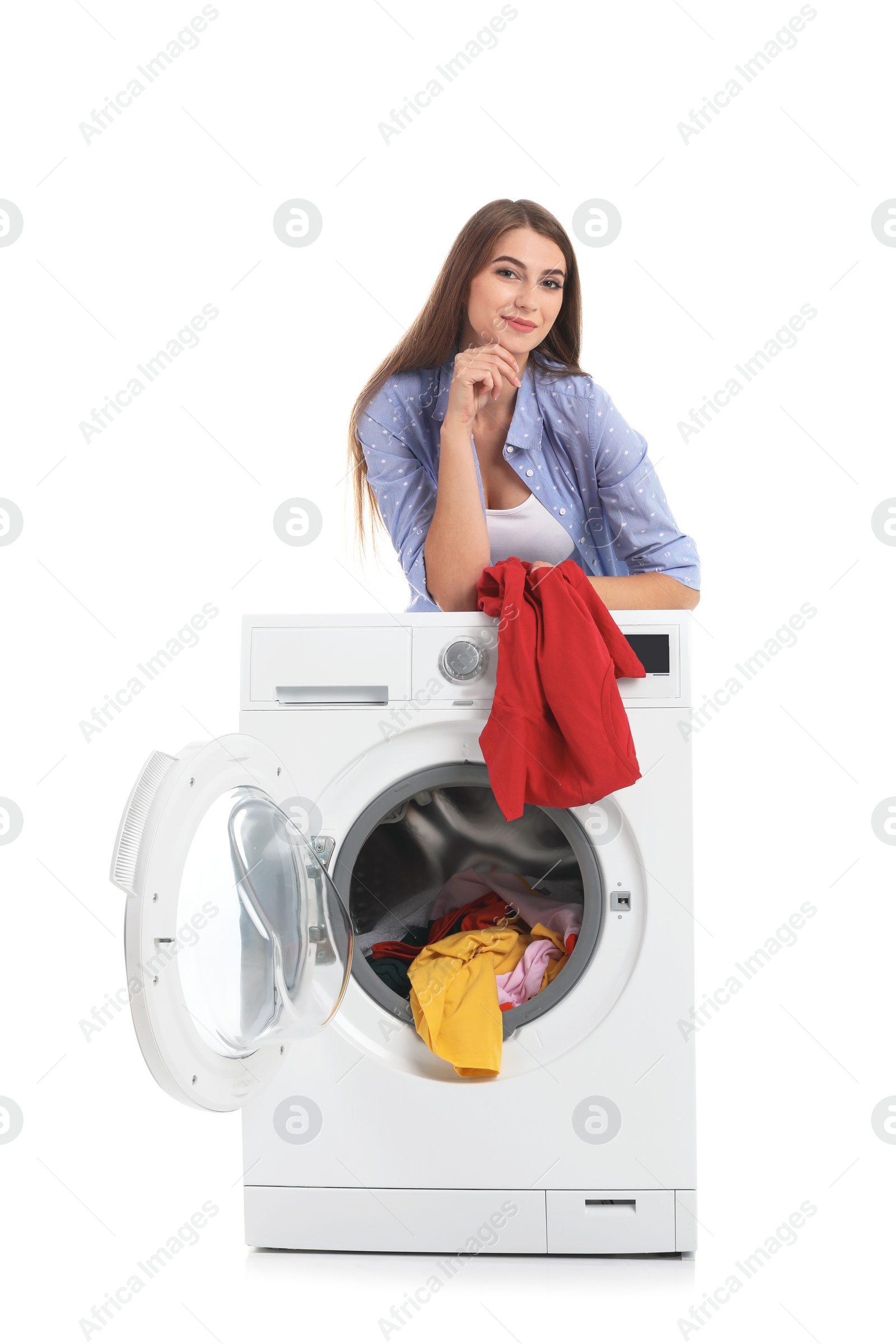 Photo of Young woman loading washing machine with dirty laundry on white background