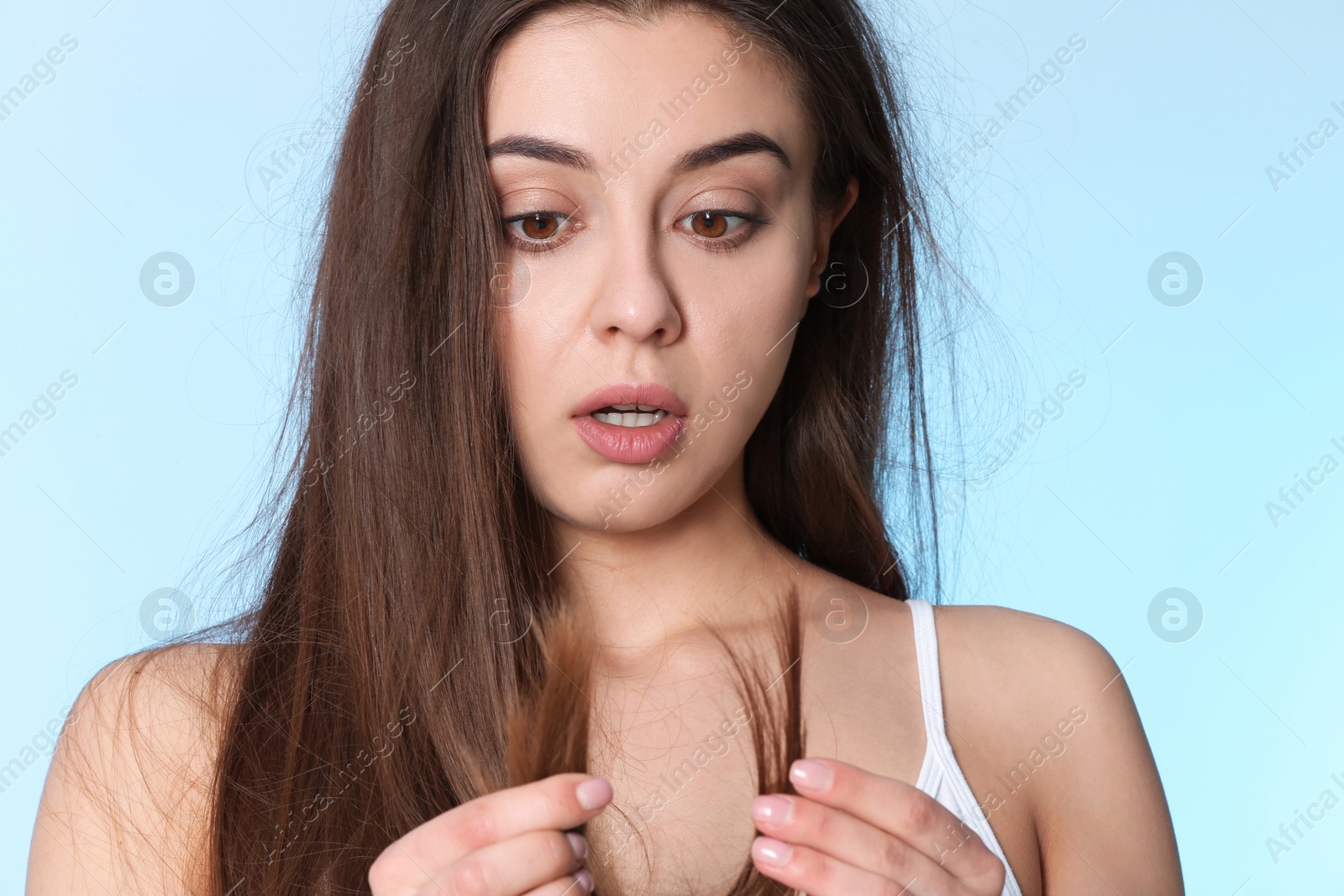 Photo of Emotional woman with damaged hair on color background. Split ends