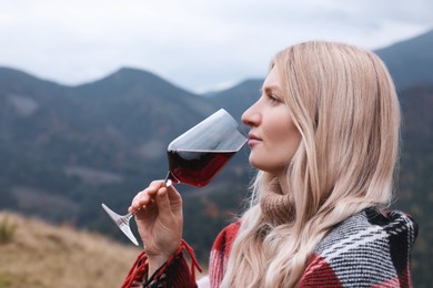 Photo of Young woman drinking wine in peaceful mountains