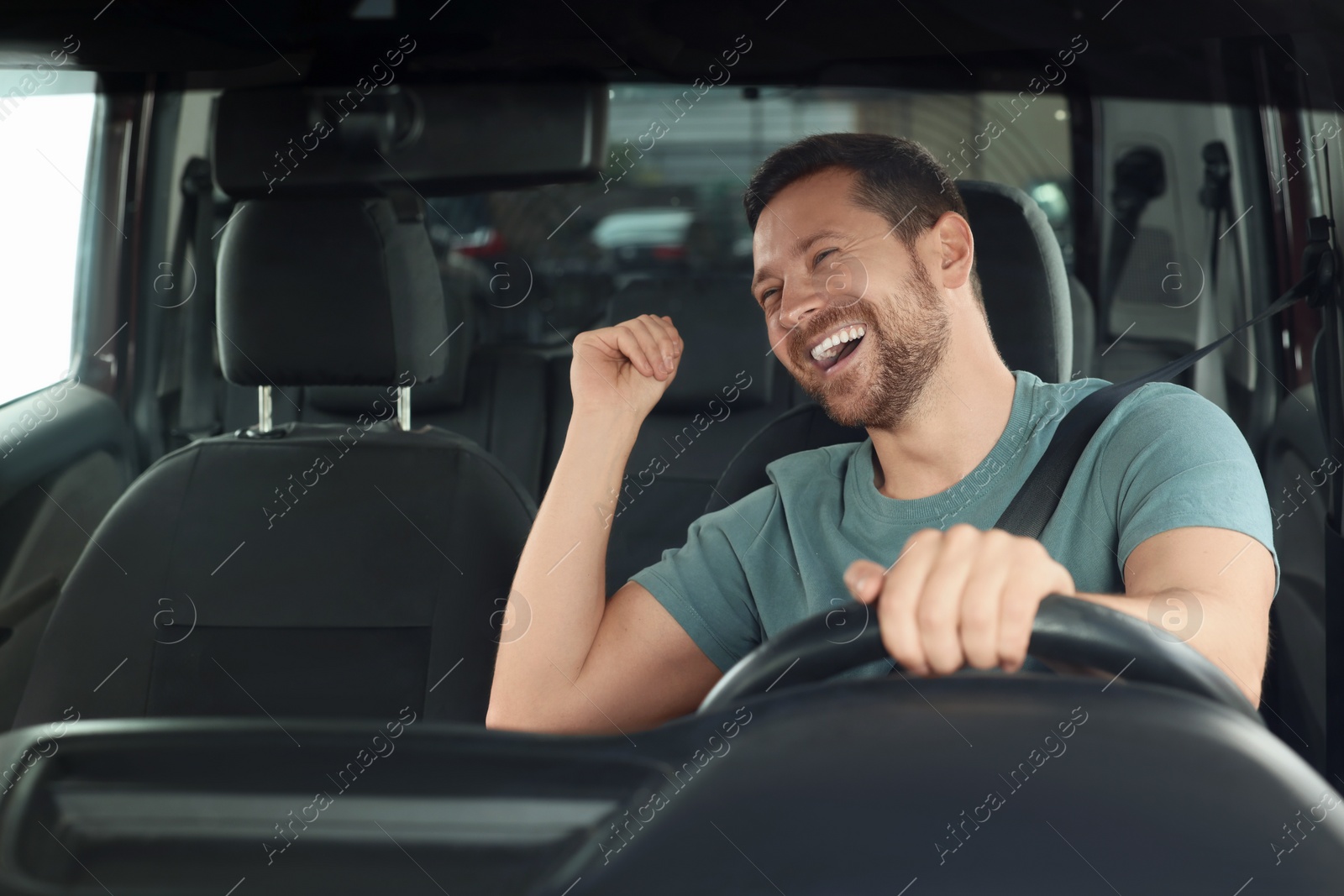 Photo of Listening to radio. Handsome man enjoying music in car, view through windshield