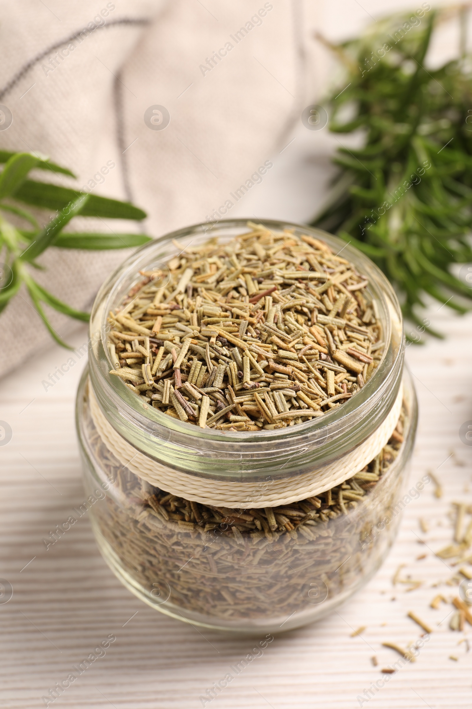 Photo of Glass jar with dry rosemary on white wooden table, closeup