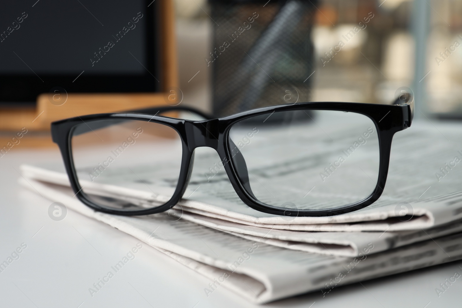 Photo of Stack of newspapers and glasses on white table indoors, closeup