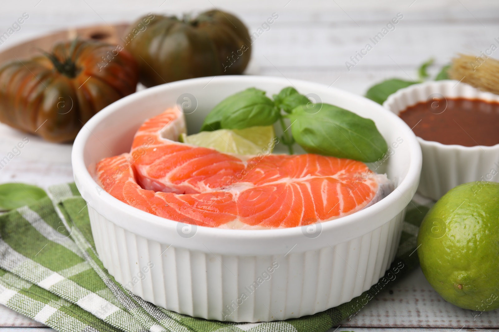 Photo of Fresh marinade, fish and lime on white wooden table, closeup