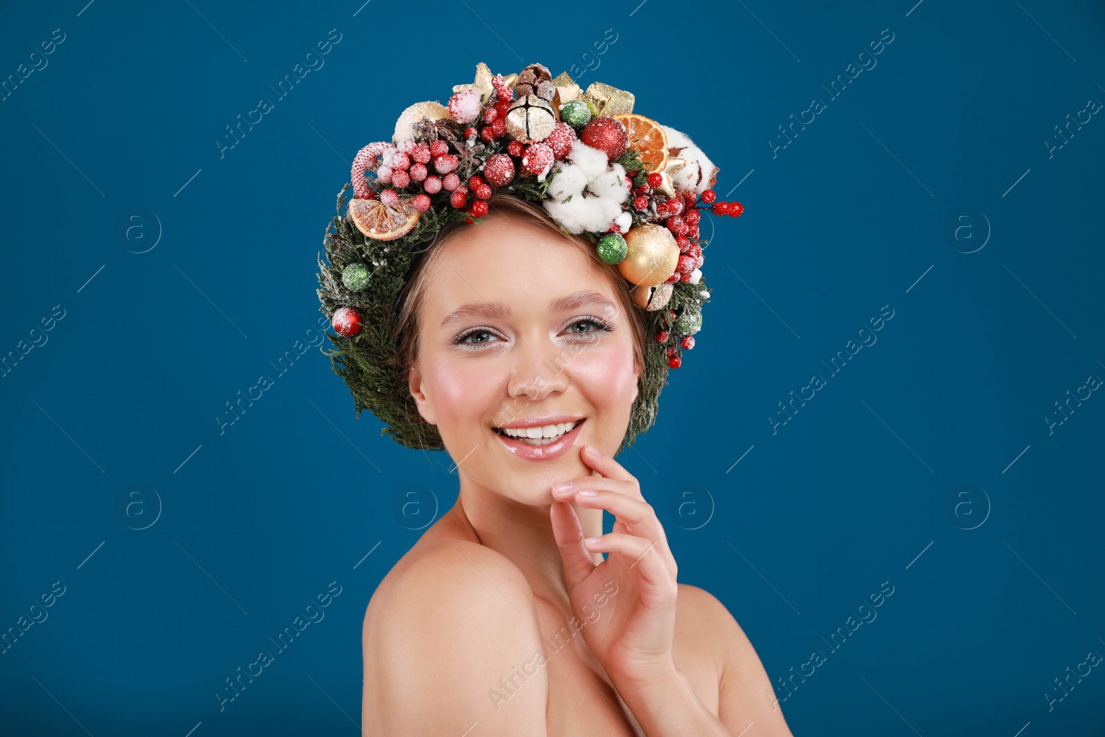 Photo of Beautiful young woman wearing Christmas wreath on blue background