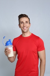 Photo of Portrait of man with bottle of protein shake on color background