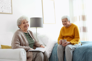 Photo of Elderly women spending time together in bedroom. Senior people care