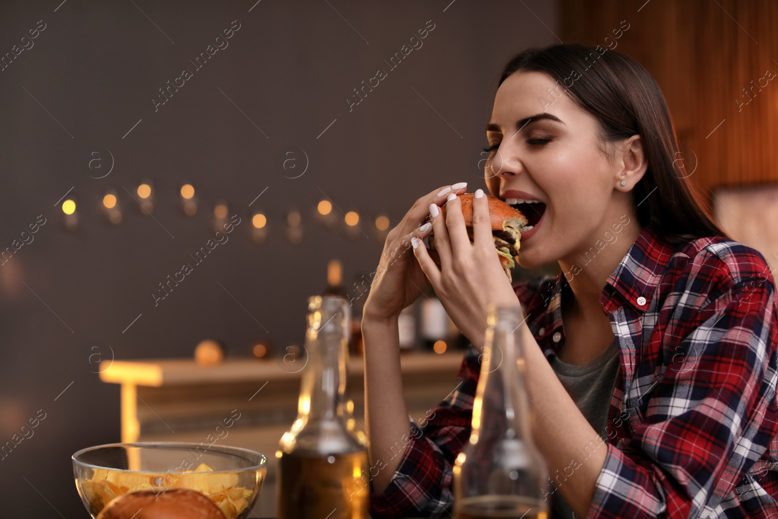 Photo of Young woman eating tasty burger in cafe