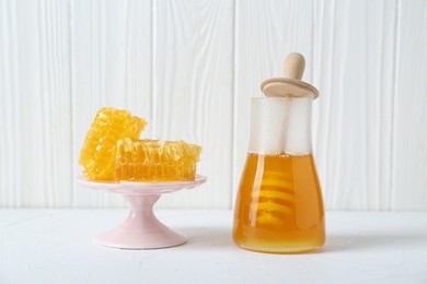 Stand with natural honeycombs and honey on white table