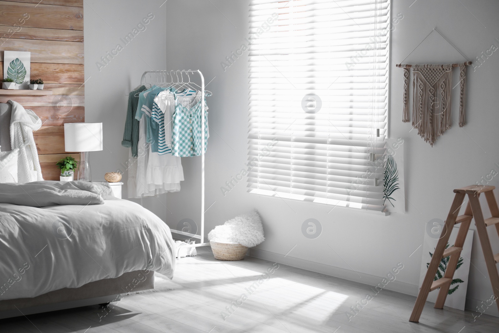 Photo of Stylish bedroom interior with clothing rack and large window