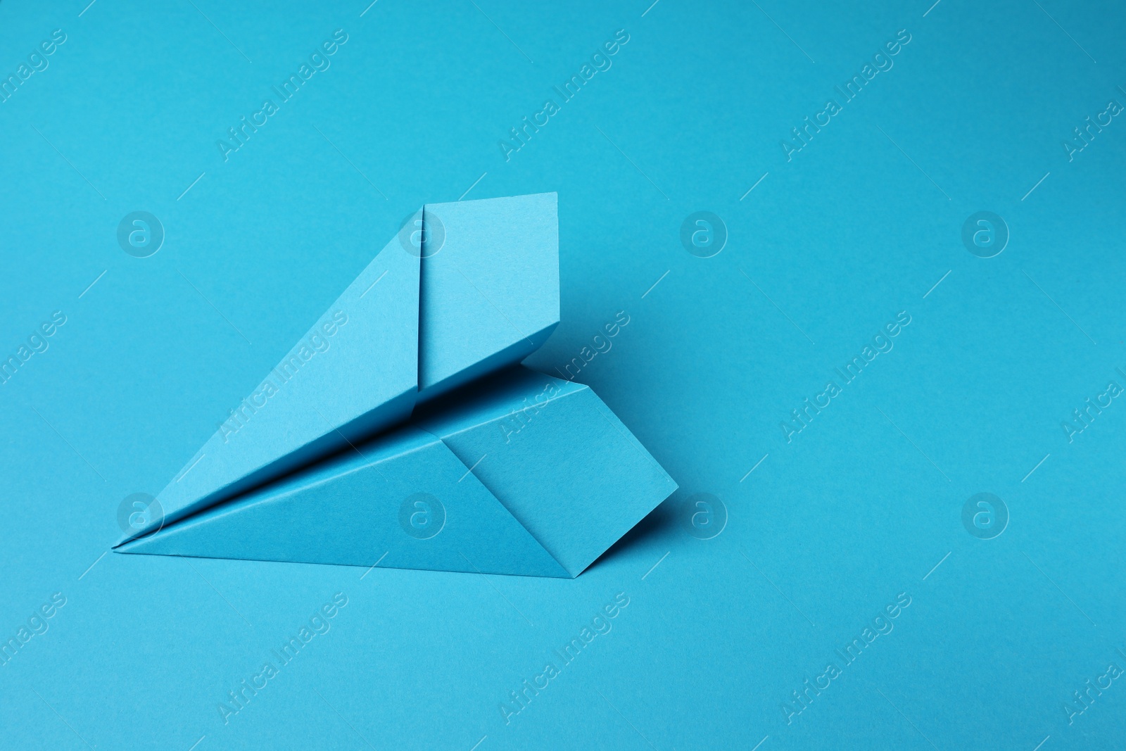 Photo of Handmade paper plane on light blue background, space for text