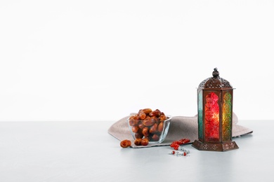 Muslim lamp, dates and prayer beads on table against white background. Space for text