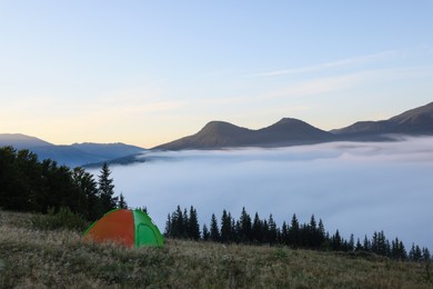 Photo of Picturesque mountain landscape with camping tent in foggy morning. Space for text