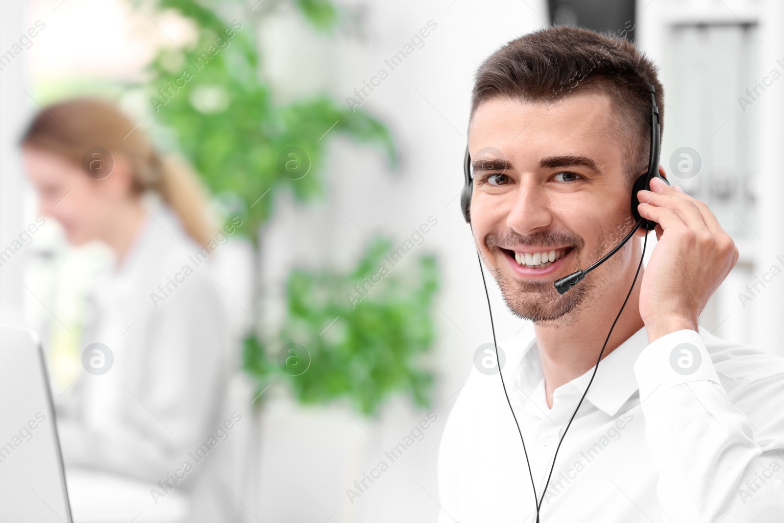 Photo of Young male receptionist with headset in office