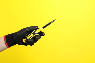 Photo of Woman holding screwdriver on yellow background, closeup. Space for text