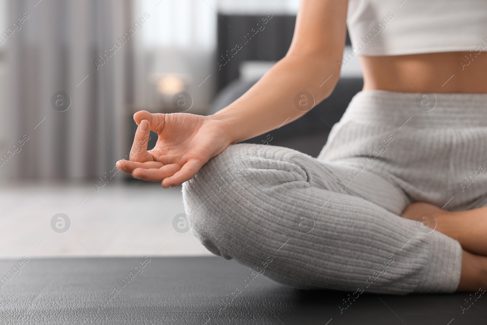 Photo of Woman practicing Padmasana on yoga mat at home, closeup and space for text. Lotus pose