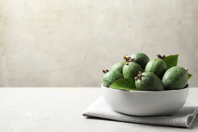 Delicious fresh feijoas in bowl on light grey table. Space for text