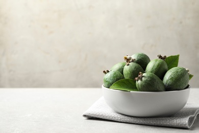 Photo of Delicious fresh feijoas in bowl on light grey table. Space for text