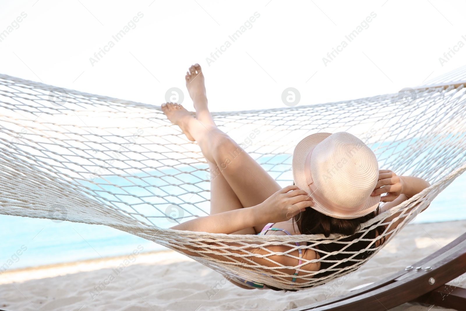 Photo of Young woman resting in hammock at seaside. Summer vacation