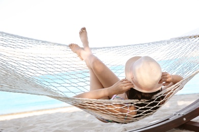 Photo of Young woman resting in hammock at seaside. Summer vacation