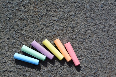 Photo of Colorful chalk sticks on asphalt, flat lay. Space for text