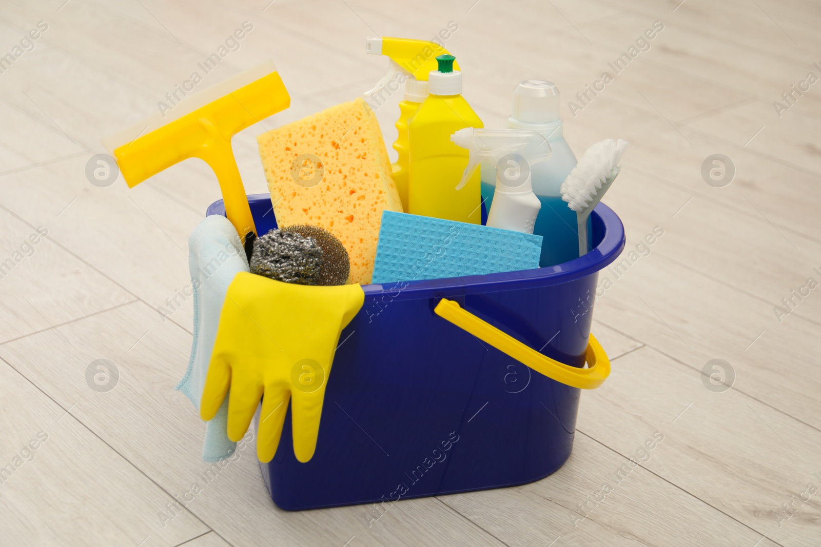 Photo of Different cleaning supplies in bucket on floor at home