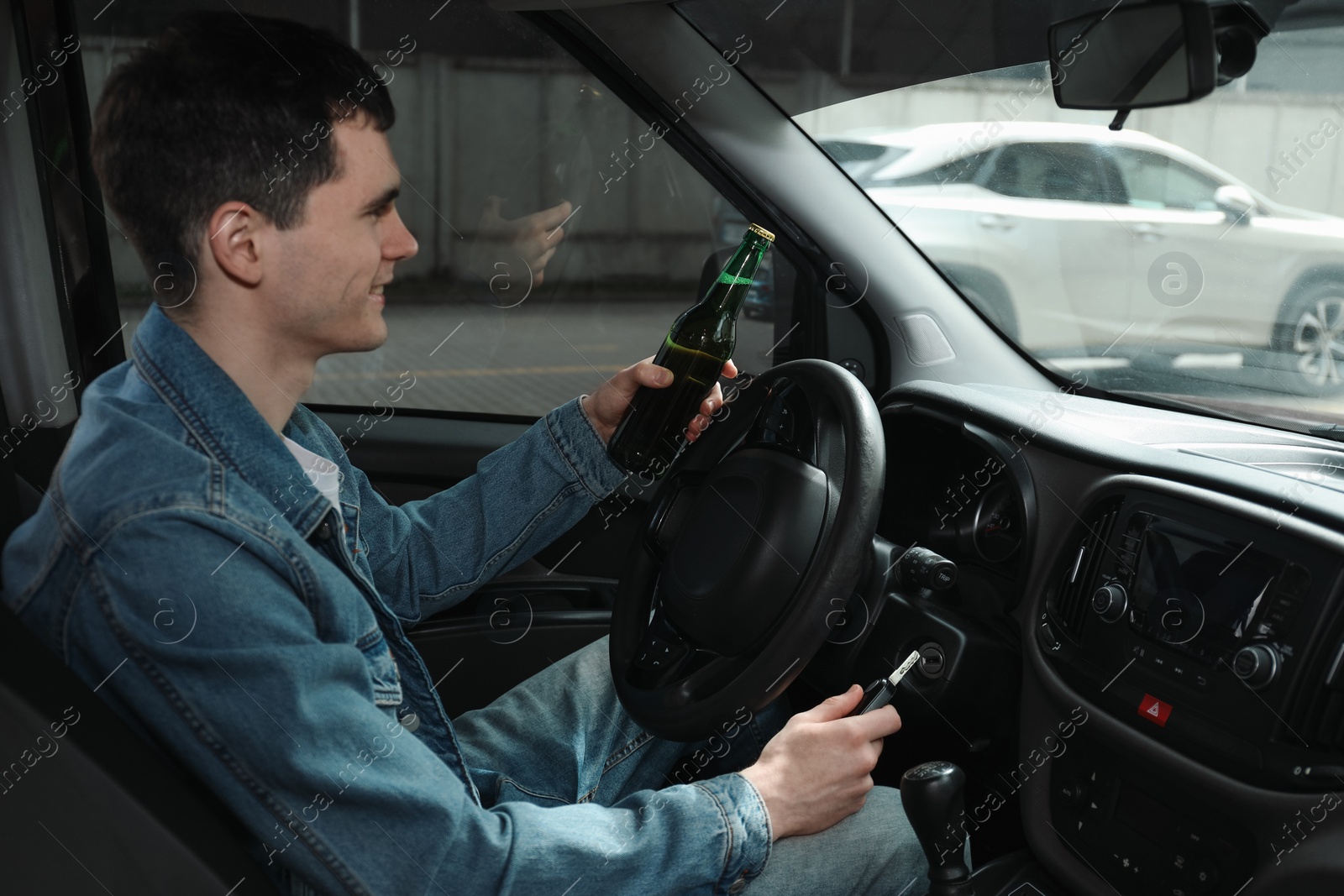 Photo of Smiling man with bottle of beer driving car. Don't drink and drive concept