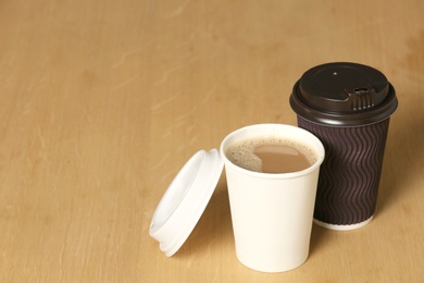 Photo of Cardboard cups of coffee on wooden background. Space for text