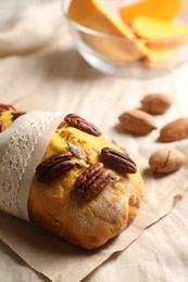 Photo of Delicious pumpkin bread with pecan nuts on table cloth, closeup