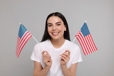 Photo of 4th of July - Independence Day of USA. Happy woman with American flags on light grey background