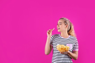 Photo of Woman eating potato chips on color background. Space for text