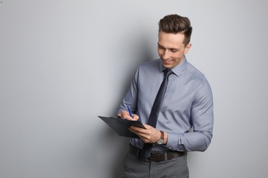 Photo of Male real estate agent with clipboard on grey background