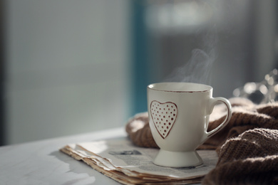 Delicious morning coffee, newspaper and knitted sweater on white table indoors. Space for text