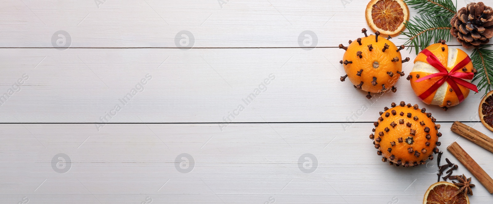 Image of Pomander balls made of tangerines with cloves, spices and fir branches on white wooden table, flat lay with space for text. Banner design