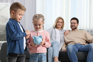 Photo of Family budget. Children with piggy bank and their parents at home, selective focus