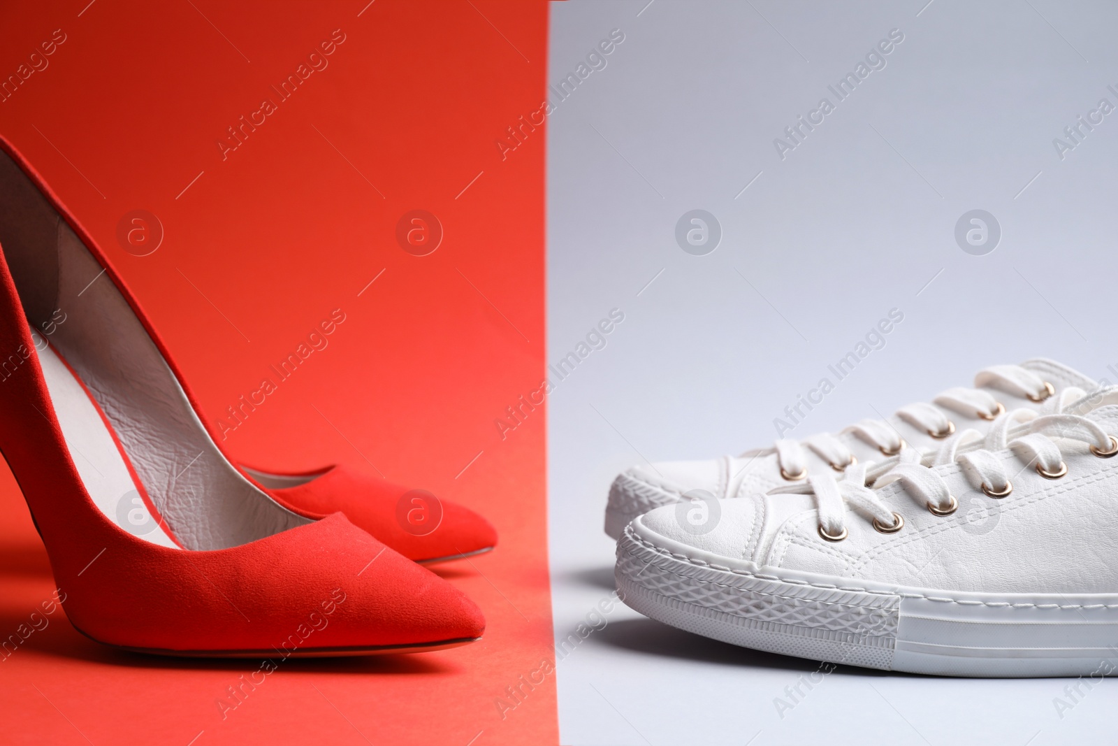 Photo of High heeled shoes and sneakers on color background