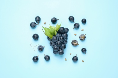 Photo of Bunch of ripe grapes with green leaves on light blue background, flat lay