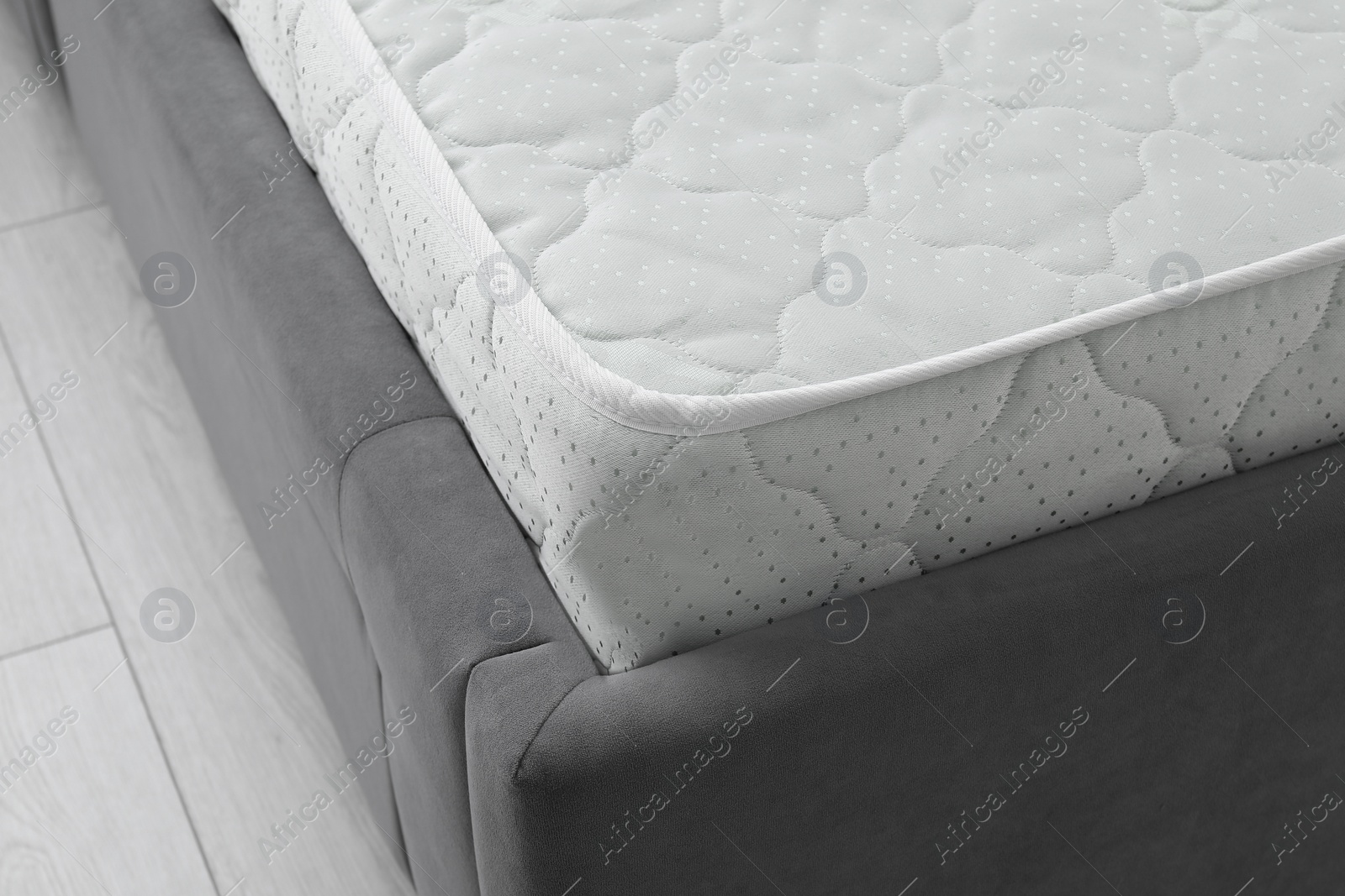Photo of New soft mattress on grey bed indoors, closeup