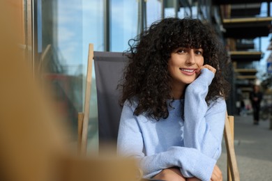 Photo of Happy young woman in stylish light blue sweater outdoors. Space for text