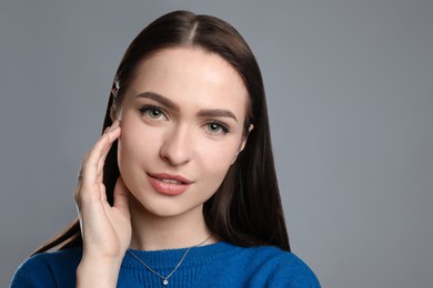 Portrait of beautiful young woman on grey background