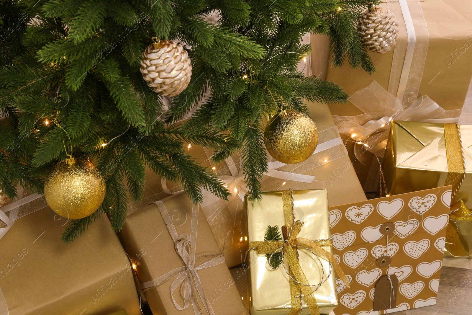 Photo of Pile of gift boxes near Christmas tree with fairy lights