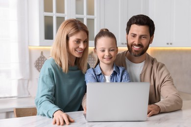 Photo of Happy family with laptop at white table indoors