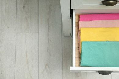 Chest of drawers with different folded clothes indoors, top view. Space for text