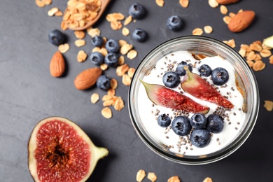Photo of Tasty homemade granola with yogurt on dark grey table, flat lay. Healthy breakfast