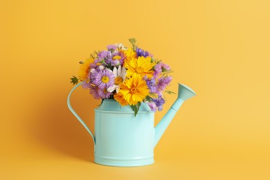 Photo of Light blue watering can with beautiful flowers on yellow background