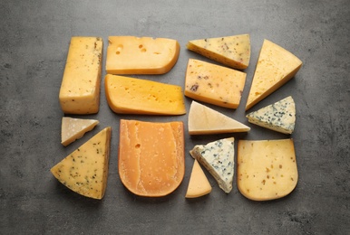 Different kinds of delicious cheese on stone background, top view