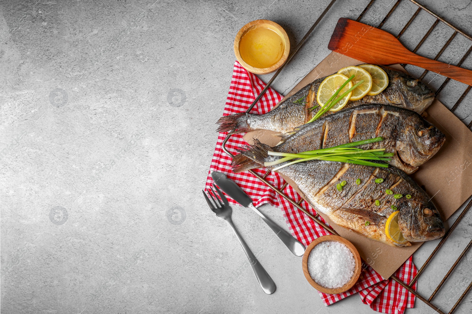 Photo of Seafood. Delicious baked fish served with green onion and lemon on light textured table, flat lay. Space for text