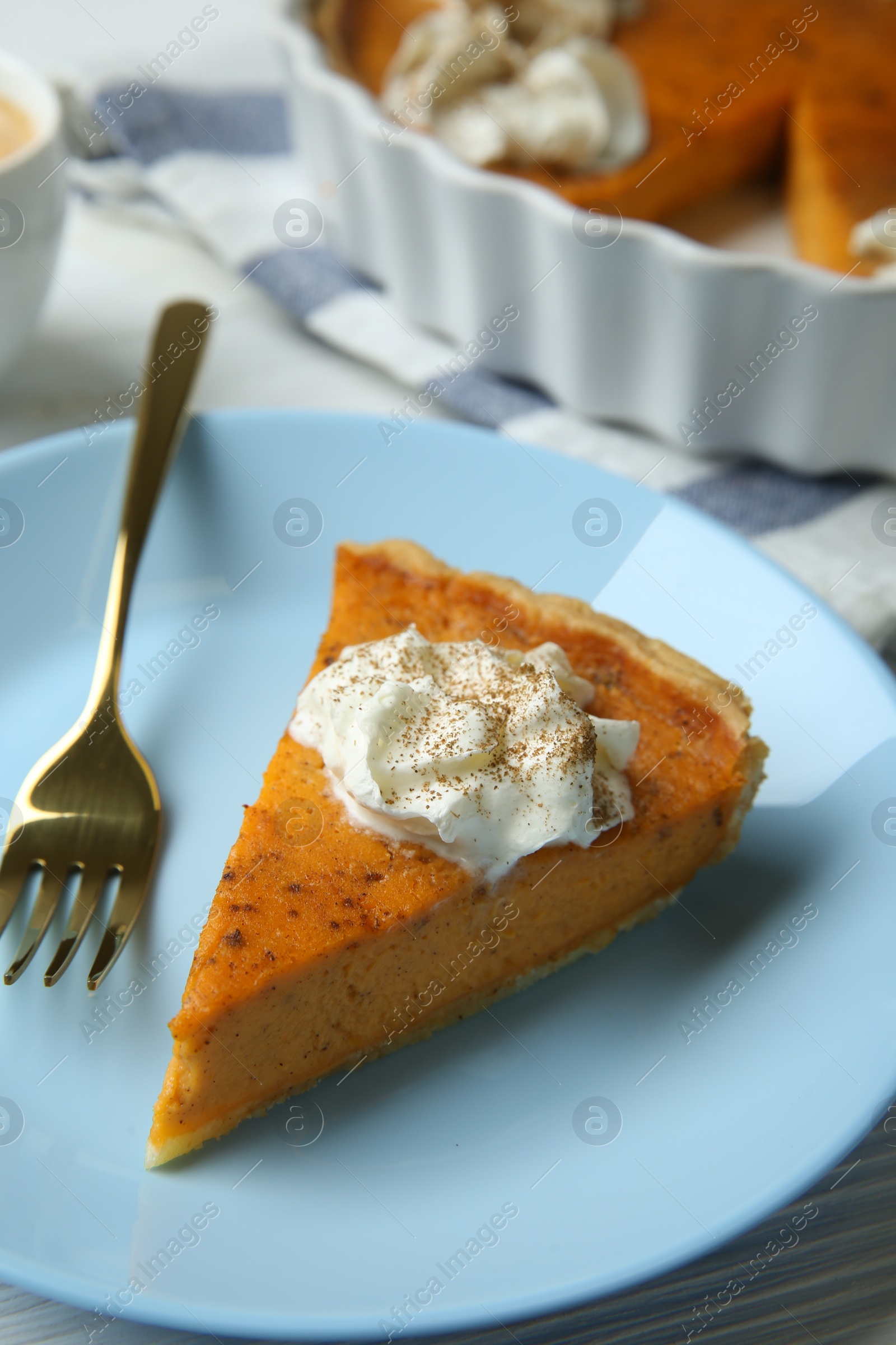 Photo of Delicious pumpkin pie with whipped cream and fork on white table