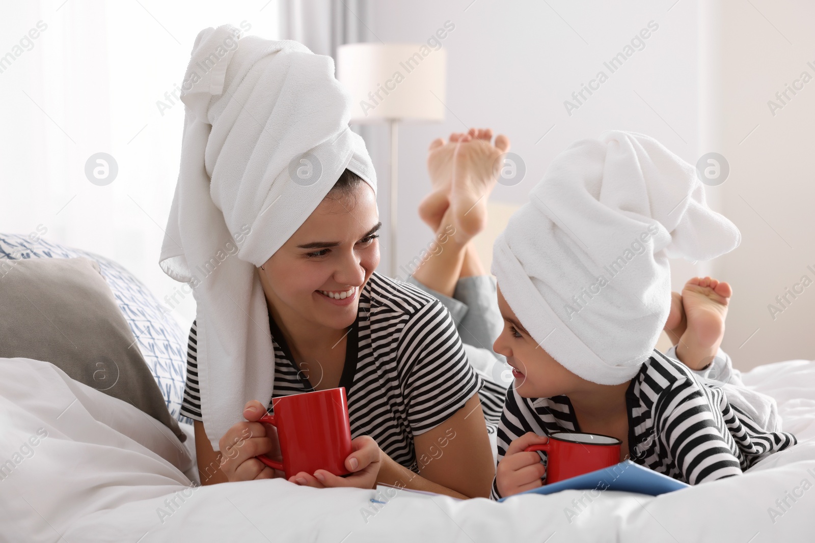 Photo of Young mother and her daughter spending time together on bed at home