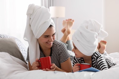 Photo of Young mother and her daughter spending time together on bed at home