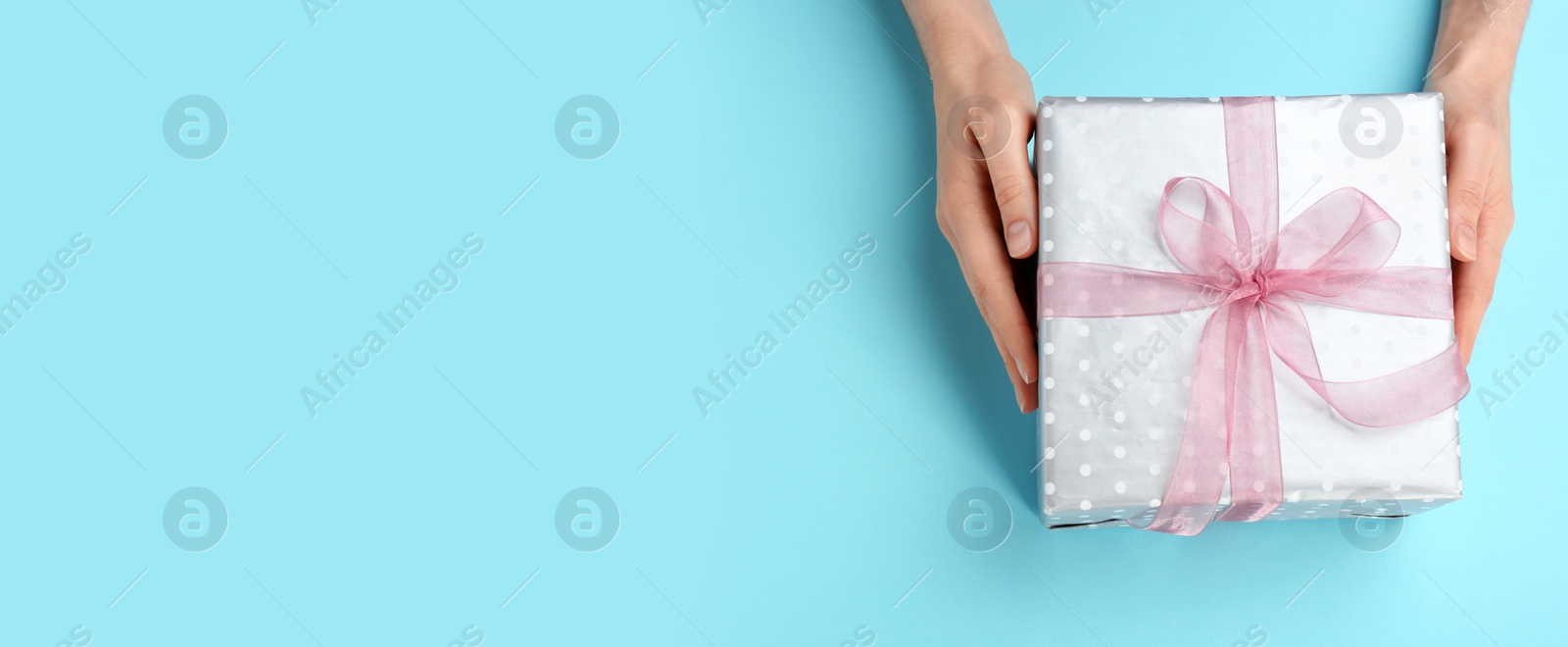 Image of Woman with gift box and space for text on light blue background, top view. Banner design